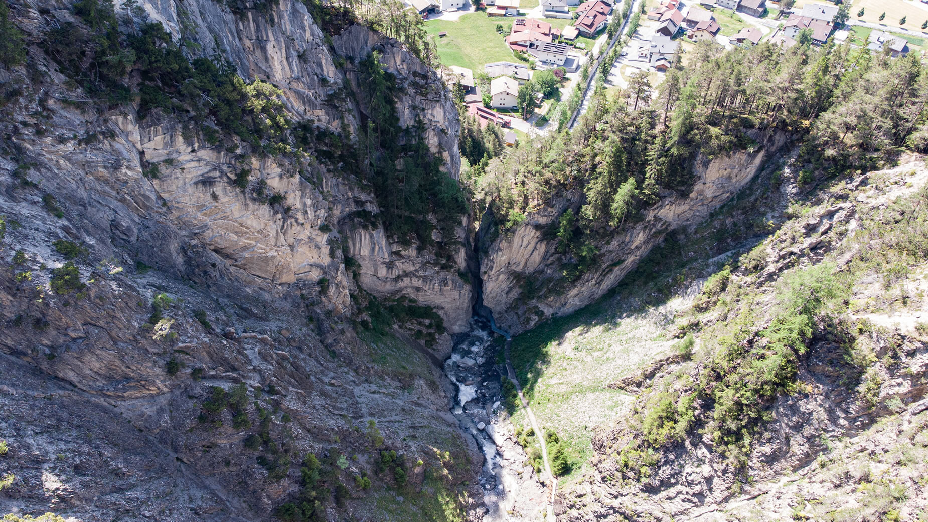 Luftaufnahme zeigt die enge Schlucht der Schnanner Klamm mit Blick auf das Dorf Schnann / Aerial view of the narrow Schnanner Klamm gorge with a view toward Schnann village