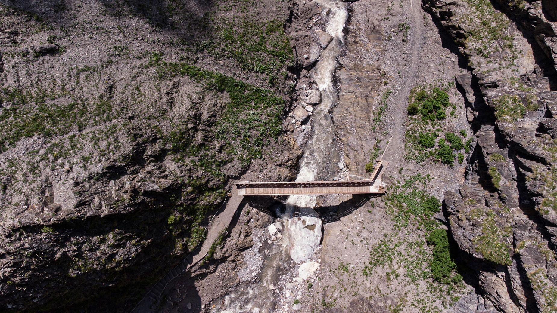 Drohnenaufnahme einer Holzbrücke über das enge Bachbett der Schnanner Klamm / Drone image of a wooden bridge over the narrow stream bed in Schnanner Klamm